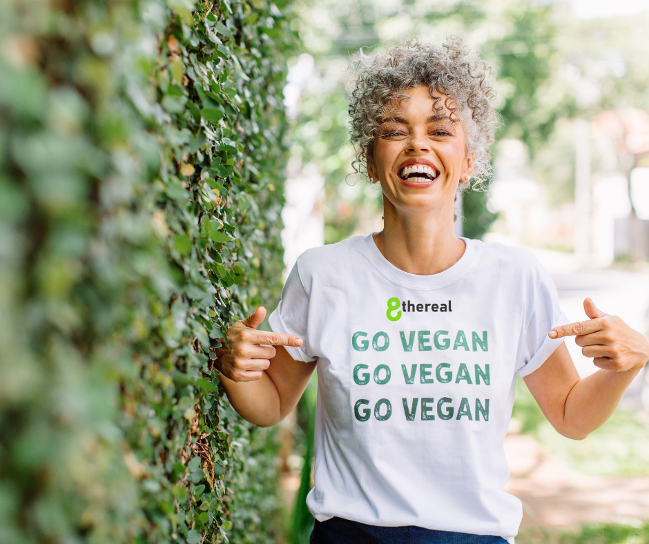 Woman depicted standing next to tree wearing white t-shirt with 8thereal under the neck and go vegan. | Best Affordable Vegan Beauty